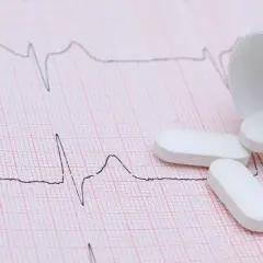 Vita tabletter, potentiellt betablockerare ångest, ligger utspridda på ett EKG-papper.