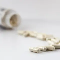En burk med litiummedicin och flera kapslar utspridda på en vit yta.