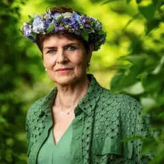 Ullakarin Nyberg med blomsterkrans i grönska.
