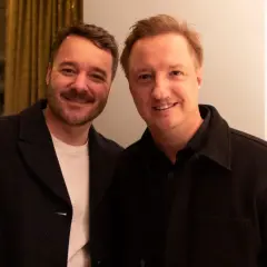 Två män ler mot kameran, deras ansikten nära varandra, vilket visar en bra relation.