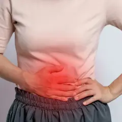 Person håller handen över magen där det lyser rött, en känsla av puls i magen stress.