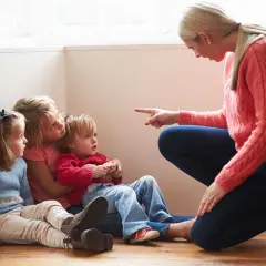 Kvinna pekar på barn som sitter på golvet. Kanske ett svårt samarbetssamtal med narcissist.