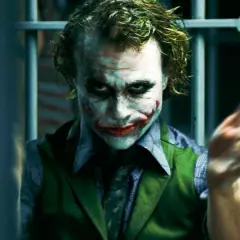 En psykopat bakom galler, med smink som en clown. Hans blick är intensiv och hans händer gestikulerar vilt. En bild som väcker tankar om sociopat vs psykopat.