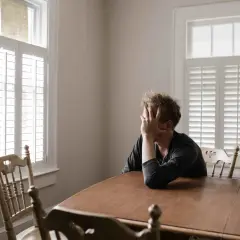 En person sitter vid ett bord med handen för ansiktet, en bild som kan symbolisera kampen att bli av med ångest utan medicin.