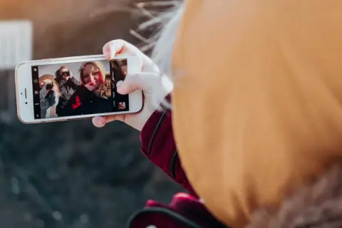 En person tar en selfie med vänner, en bild som visar hur påverkar mobilen oss negativt genom att isolera oss i digitala bubblor.