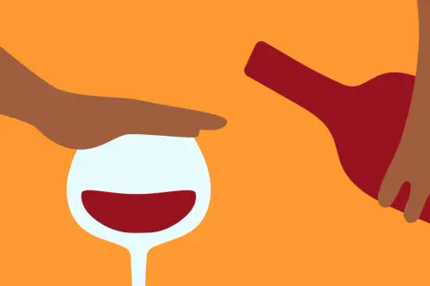 En hand stoppar ett vinglas med rött vin, medan en flaska hälls. Känslan av ångest av alkohol kan vara överväldigande.