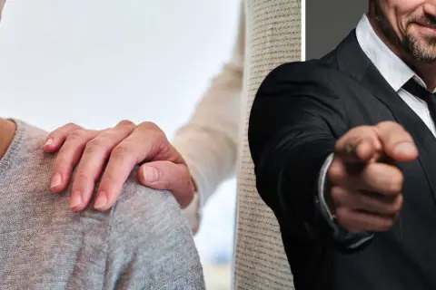 En hand vilar tröstande på en axel, medan en man i kostym pekar anklagande. En bild av att leva med en psykopat.