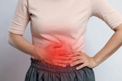 Person håller handen över magen där det lyser rött, en känsla av puls i magen stress.