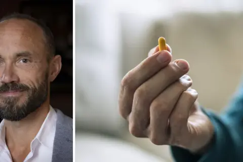 Man med skägg håller en gul kapsel, en ny medicin mot schizofreni.