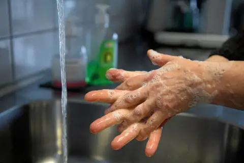 Hands being washed with soap and water in a sink.