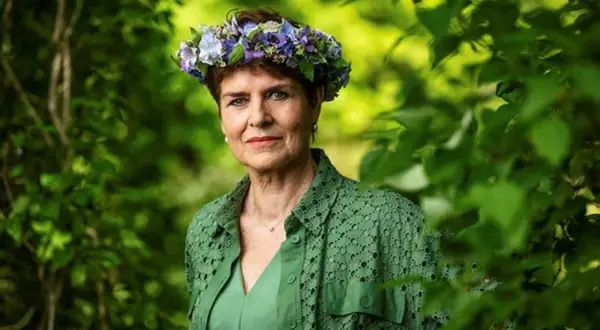 Ullakarin Nyberg med blomsterkrans i grönska.