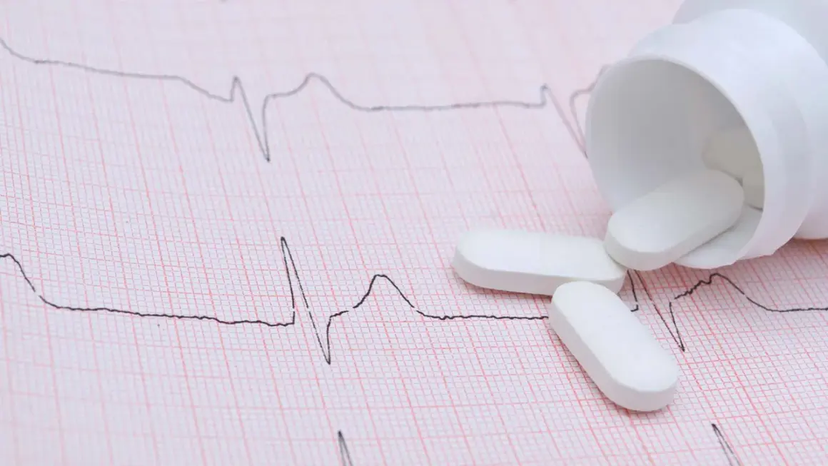 Vita tabletter, potentiellt betablockerare ångest, ligger utspridda på ett EKG-papper.