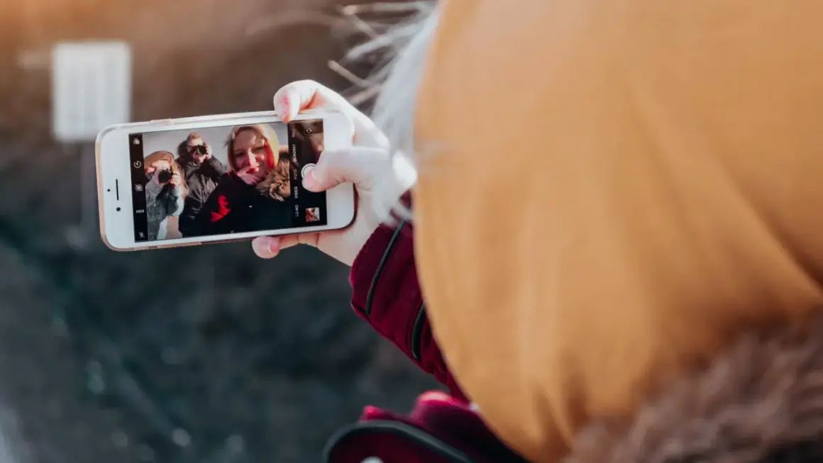 En person tar en selfie med vänner, en bild som visar hur påverkar mobilen oss negativt genom att isolera oss i digitala bubblor.