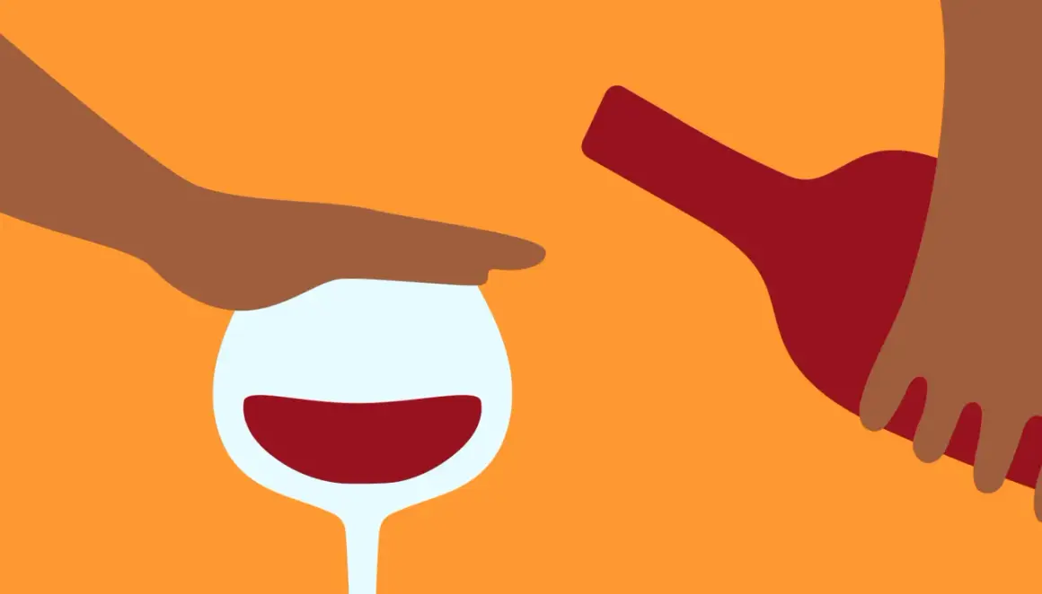 En hand stoppar ett vinglas med rött vin, medan en flaska hälls. Känslan av ångest av alkohol kan vara överväldigande.