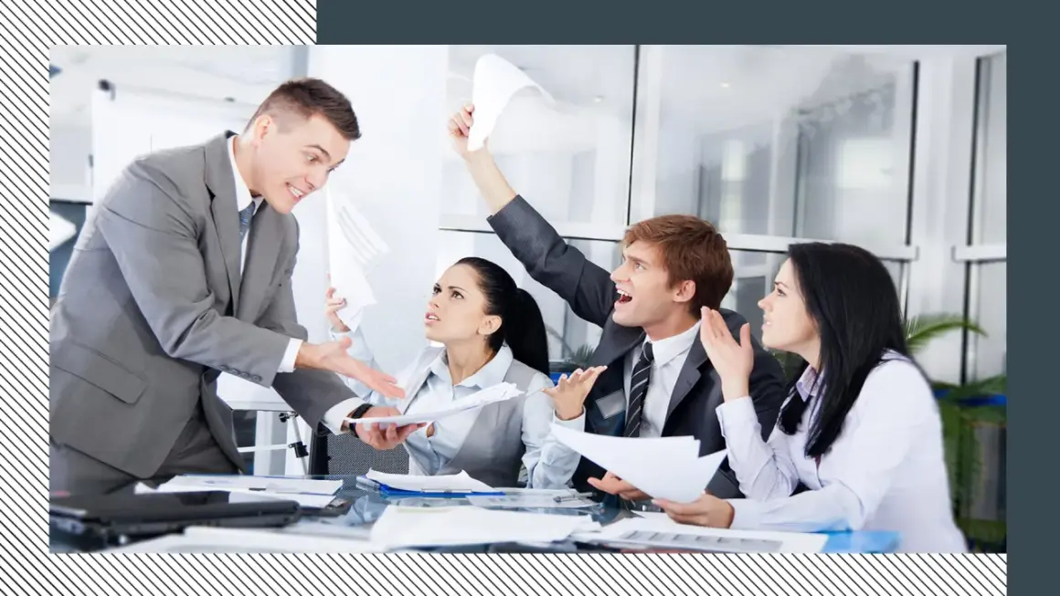 Business people in a meeting looking stressed and arguing, with papers flying.
