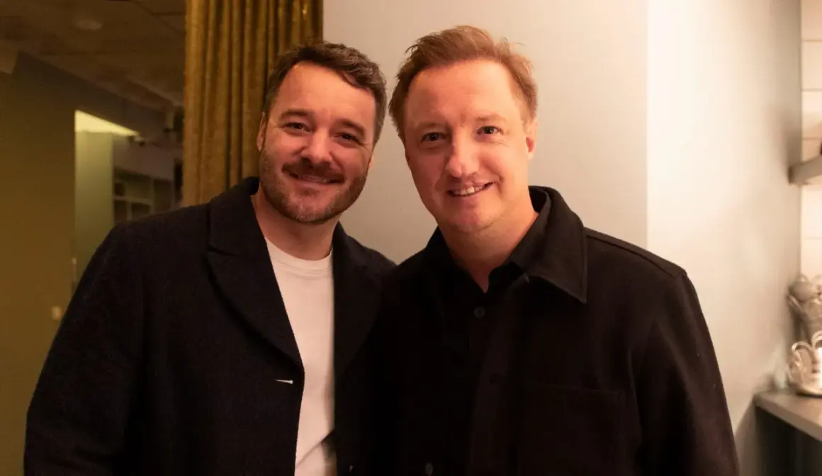 Två män ler mot kameran, deras ansikten nära varandra, vilket visar en bra relation.