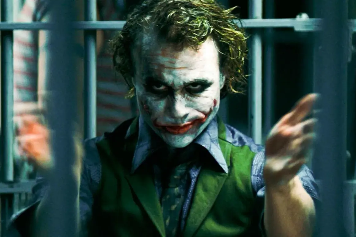 En psykopat bakom galler, med smink som en clown. Hans blick är intensiv och hans händer gestikulerar vilt. En bild som väcker tankar om sociopat vs psykopat.