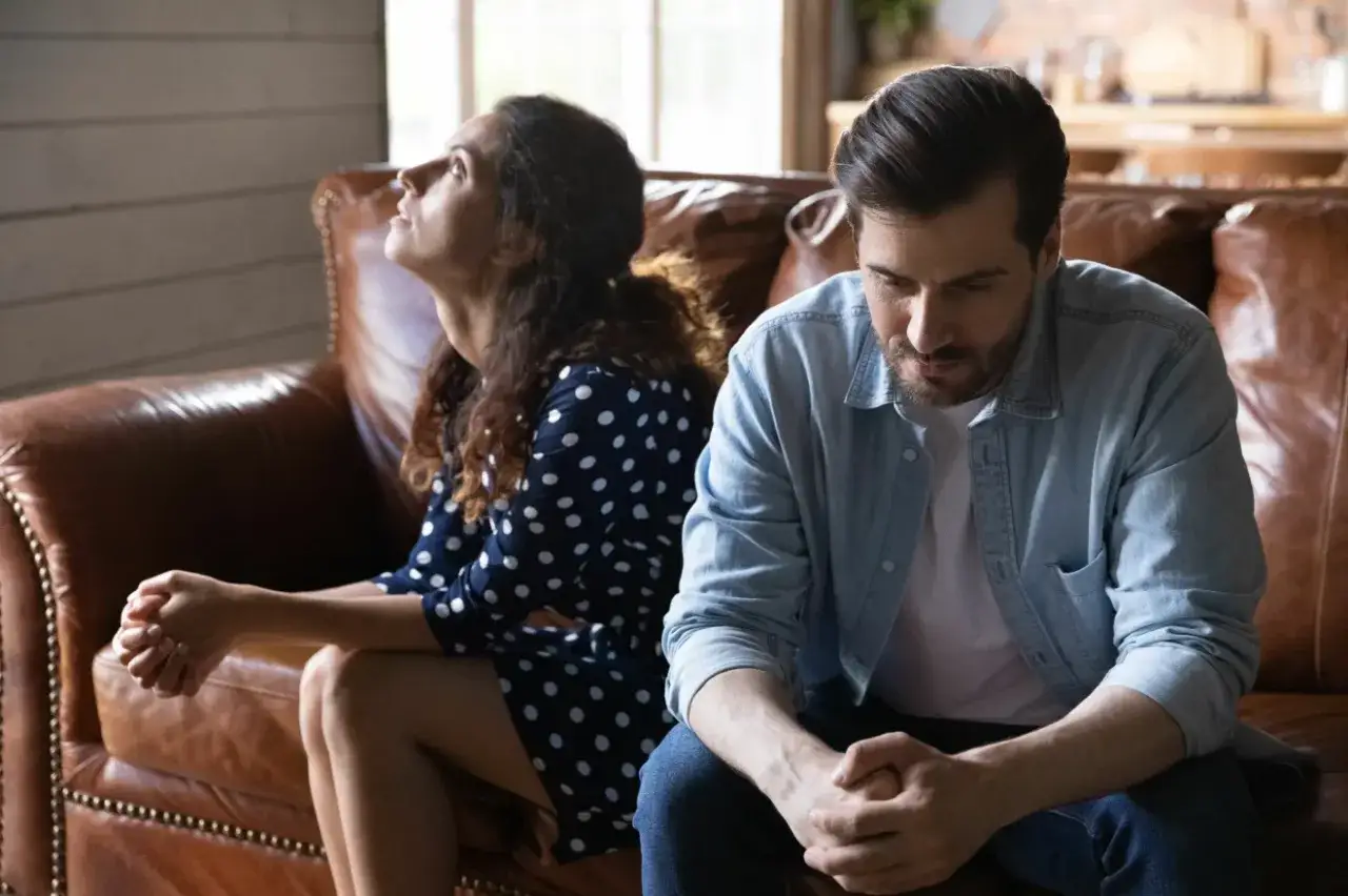 Ett par sitter p&aring; en soffa, v&auml;nda bort fr&aring;n varandra. Kvinnan tittar upp&aring;t med en sorgsen blick, mannen tittar ner. Deras kroppsspr&aring;k signalerar d&aring;lig kommunikation i relationen.