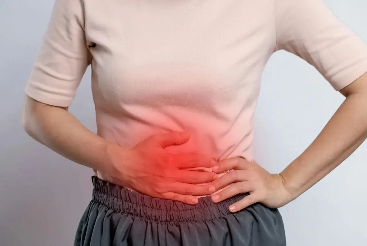 Person håller handen över magen där en röd glöd indikerar obehag, kanske en puls i magen stress.